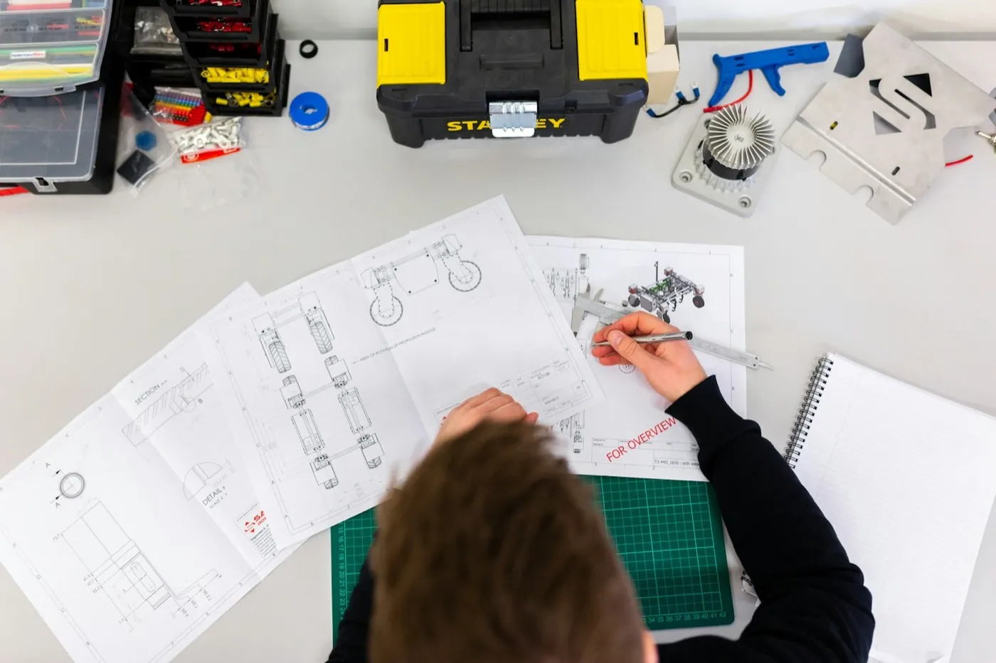 Engineer checking dimensions against technical drawings at a workbench