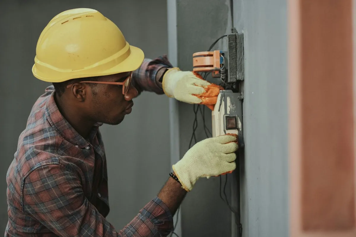 Technician in hard hat commissioning wall-mounted equipment